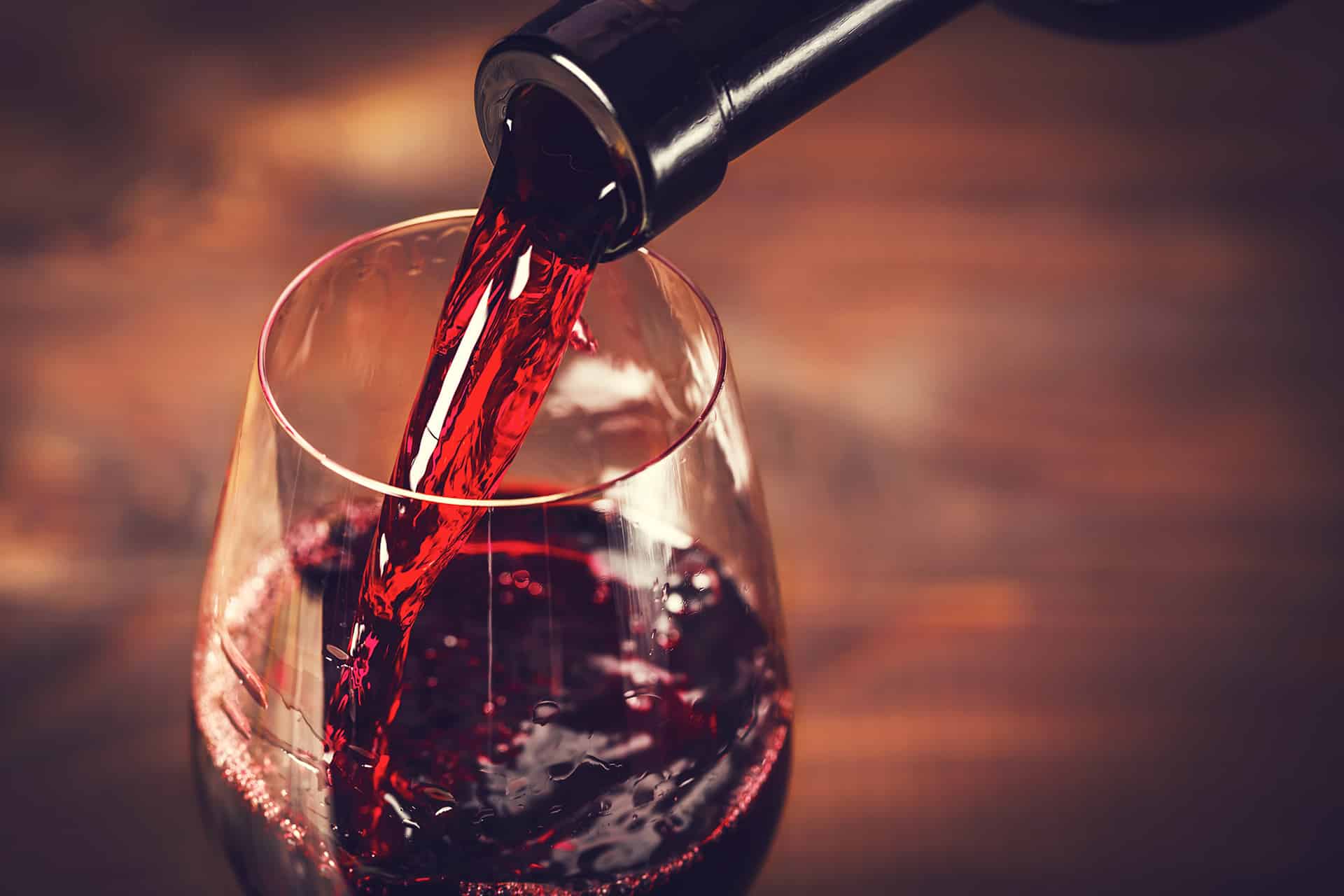 bouteille verssant du vin rouge dans un verre
